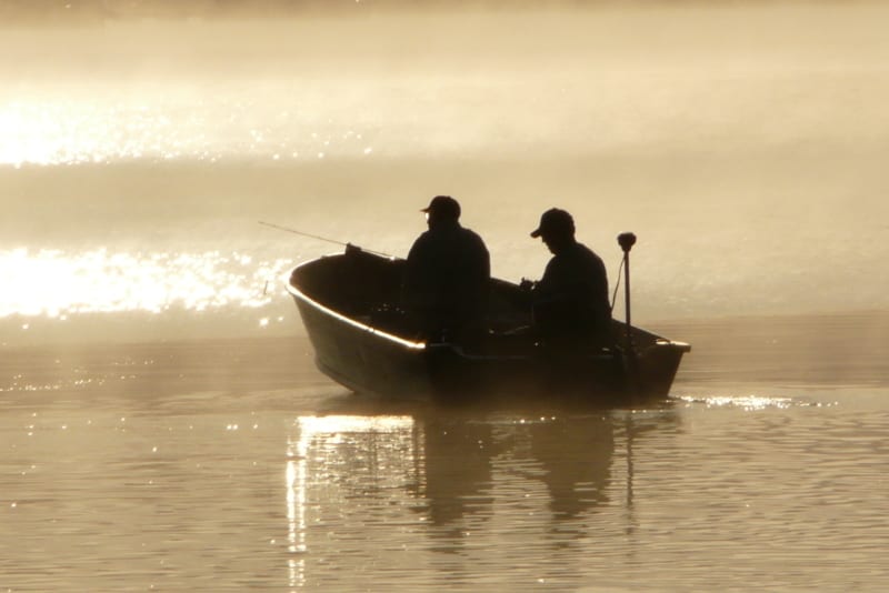 Two fishermen on the river at sunset.