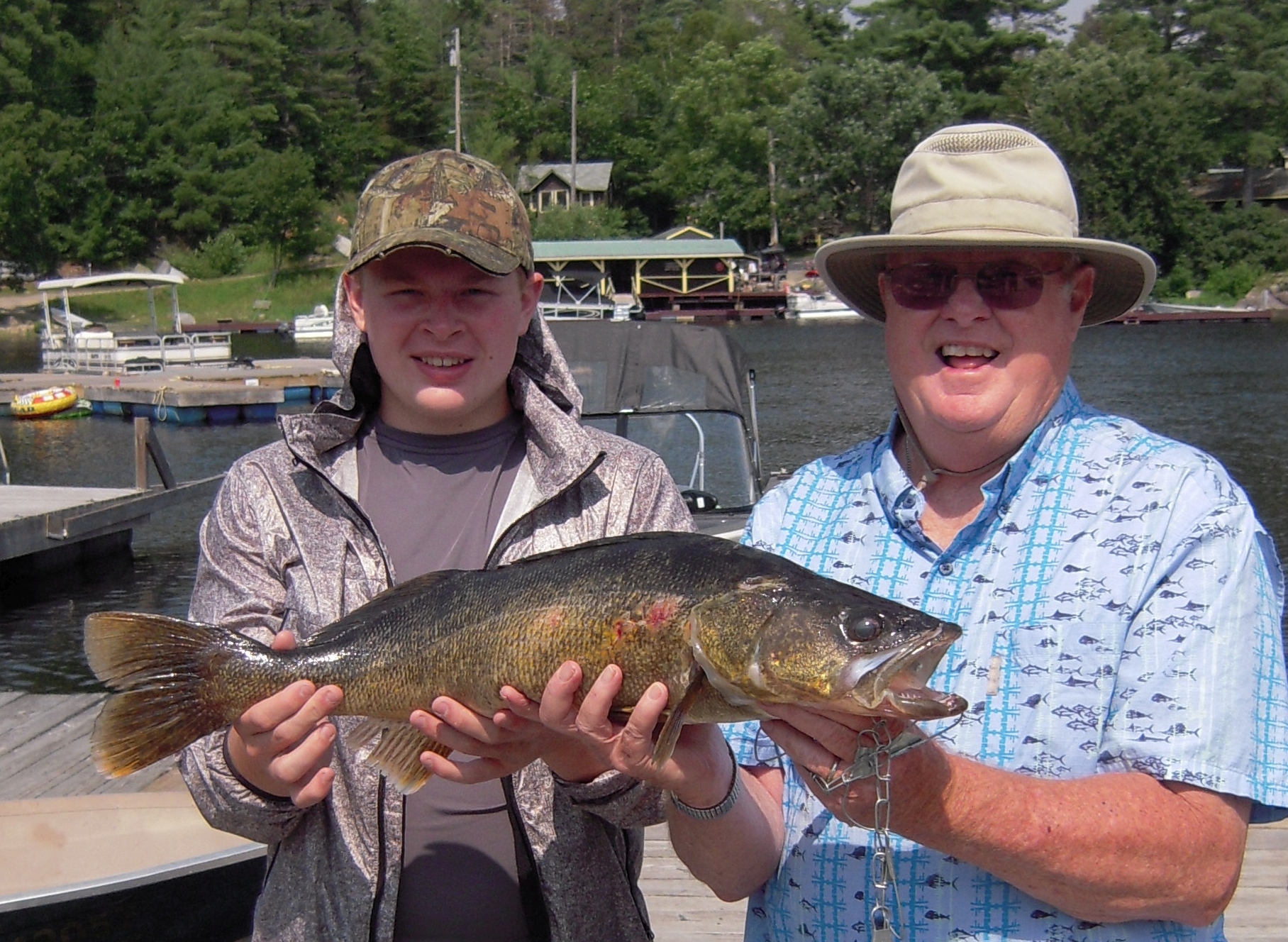 Photo of a Father and Son Holding a Giant Fish. Click Here to Learn more about our Ontario Vacations.